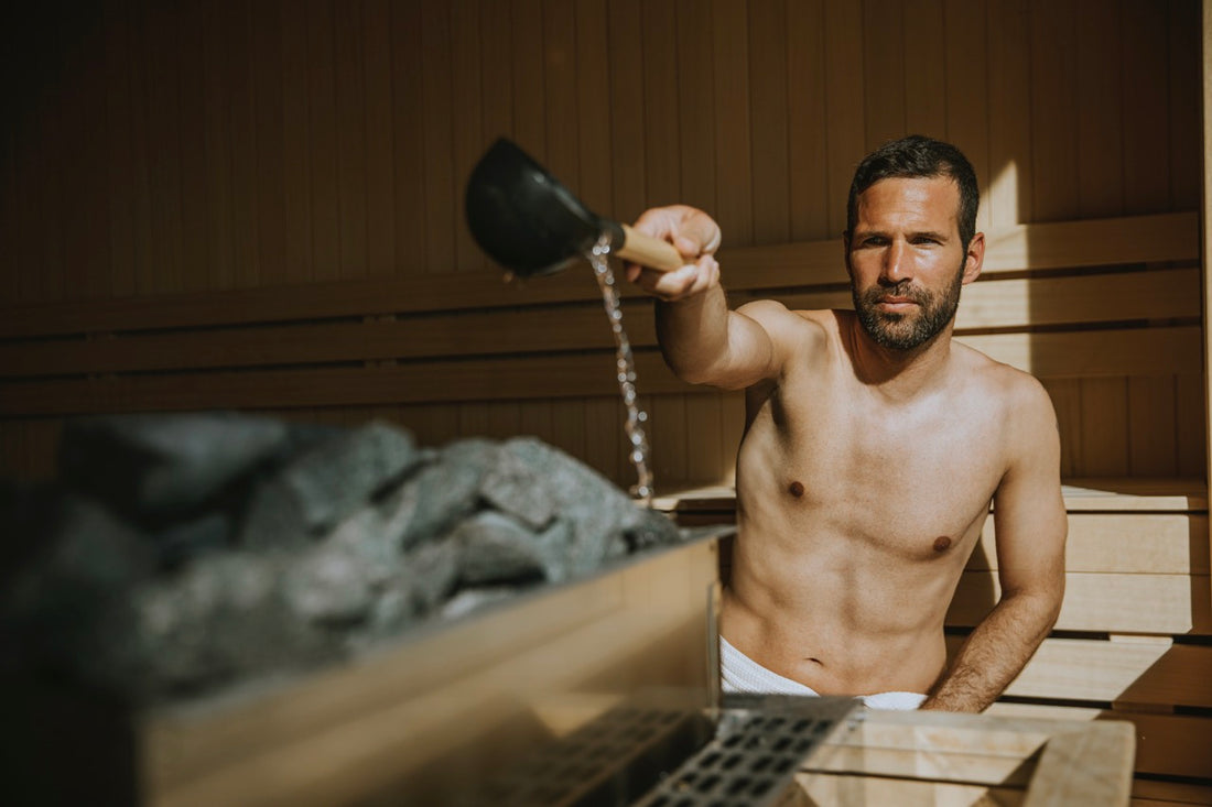 Hombre vertiendo agua sobre las piedras calientes de la sauna.