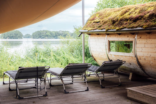 Sillas en una terraza de madera junto a una sauna.