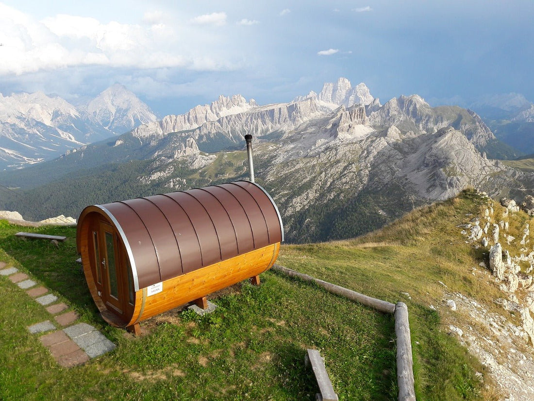 Sauna de barril en una colina con montañas al fondo.