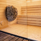 Sauna LUMI con cesta de piedra y pared de cristal.