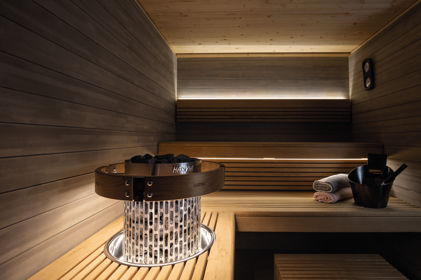 Juego de iluminación LED Harvia en sauna con piedras y cubo.