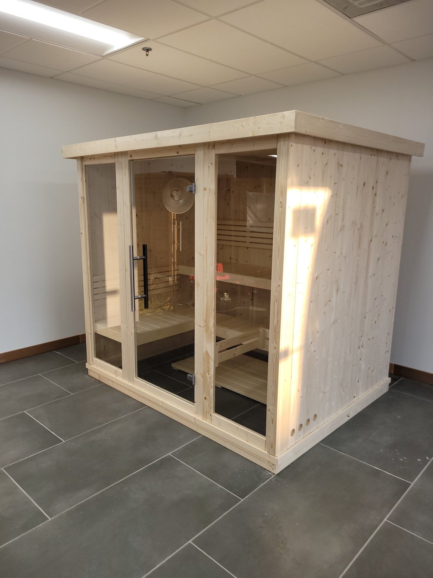 Amplia sauna cubierta con puertas de cristal templado.