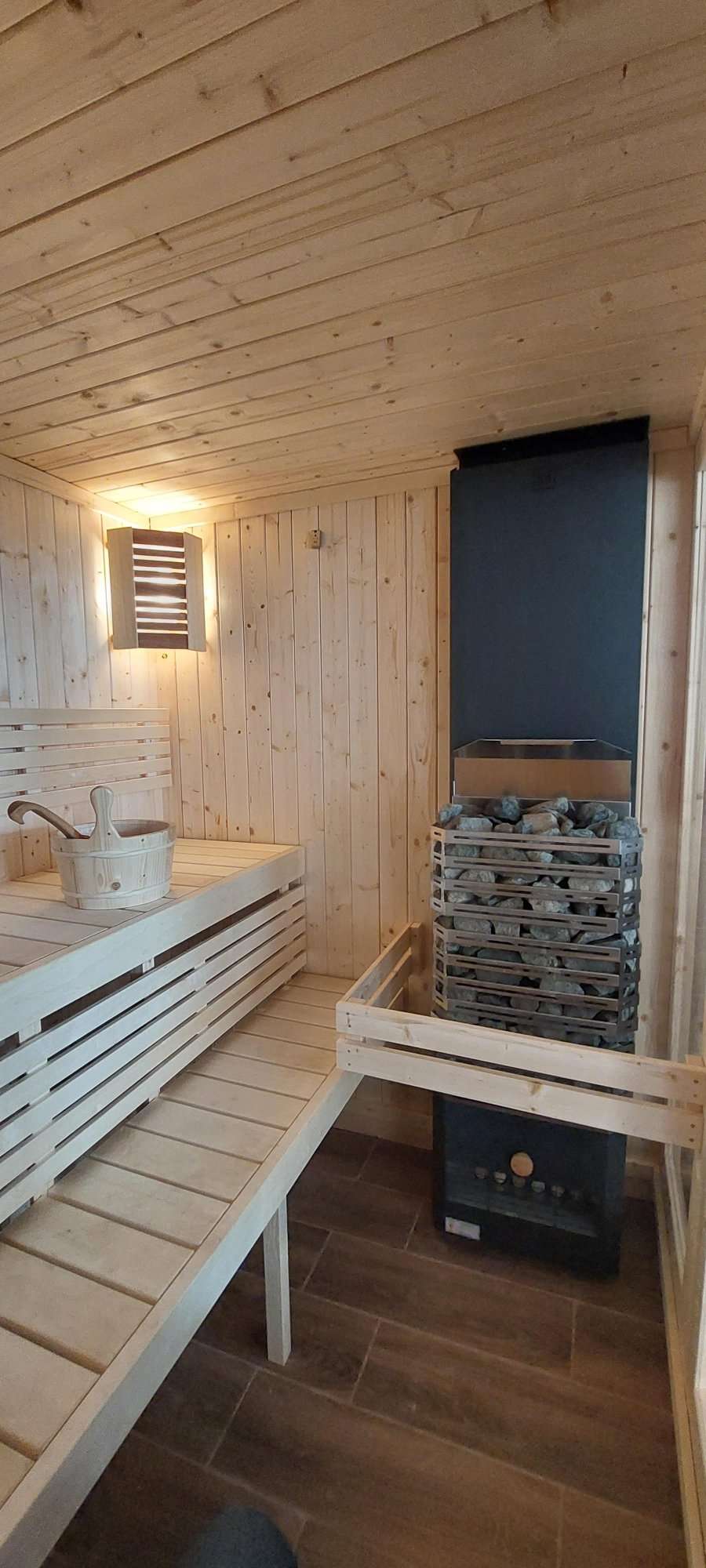 Gran sauna cubierta con cubo y piedras.