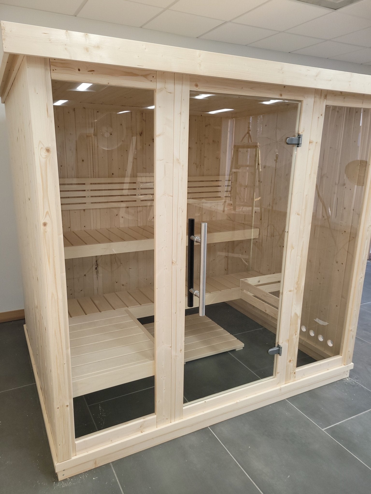 Gran sauna interior de madera con puertas de cristal.