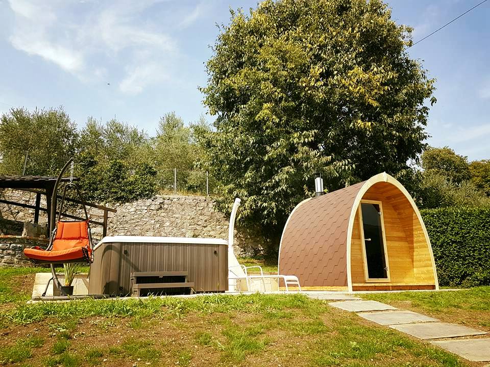 Saunamo Pod junto a una cabaña de madera y jardín.